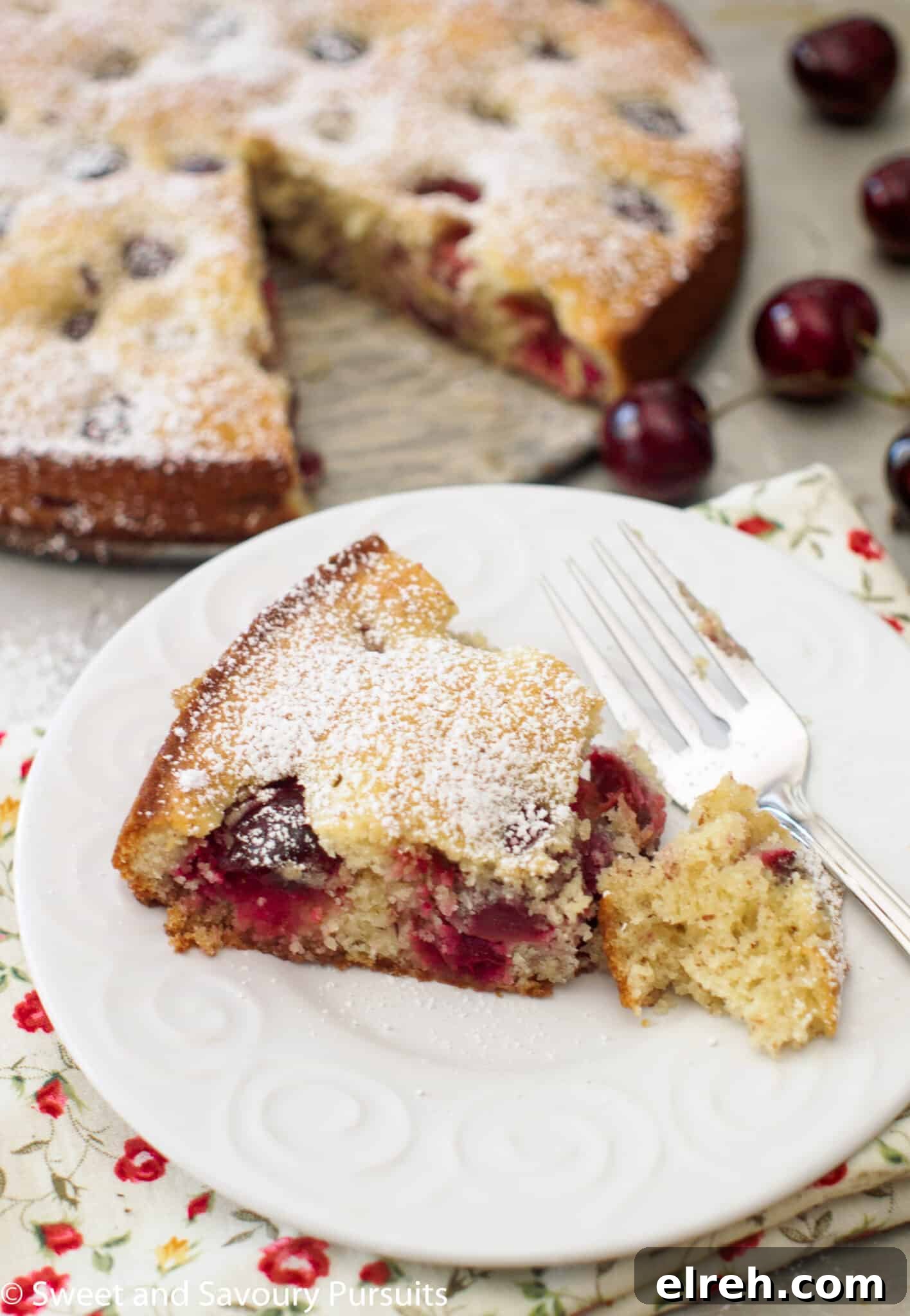 Irresistible Cherry Almond Cake with Fragrant Glaze 4 Slice of Cherry Almond Cake with a dusting of powdered sugar on white dish.