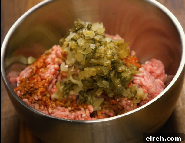 Ground pork mixed with pickled mustard greens and seasonings in a metal bowl — key topping for dan dan noodles.