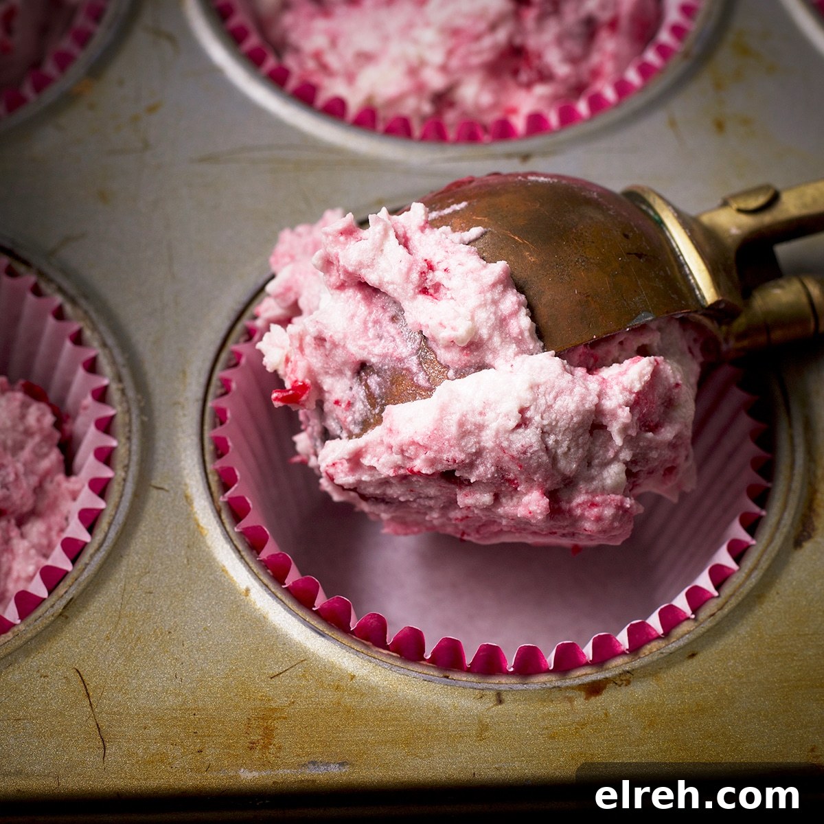 Raspberry Cupcakes Recipe with Cream Cheese Frosting 17 Using an ice cream scoop to fill paper lined cupcake cups with raspberry cupcake batter.