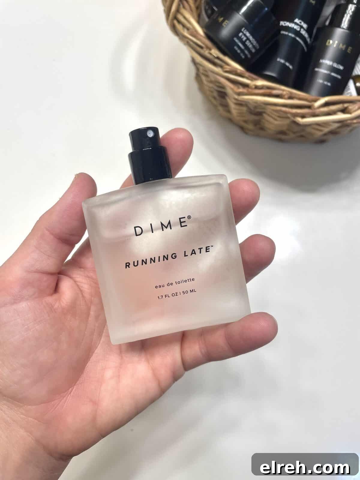 person's hand holding a bottle of dime perfume