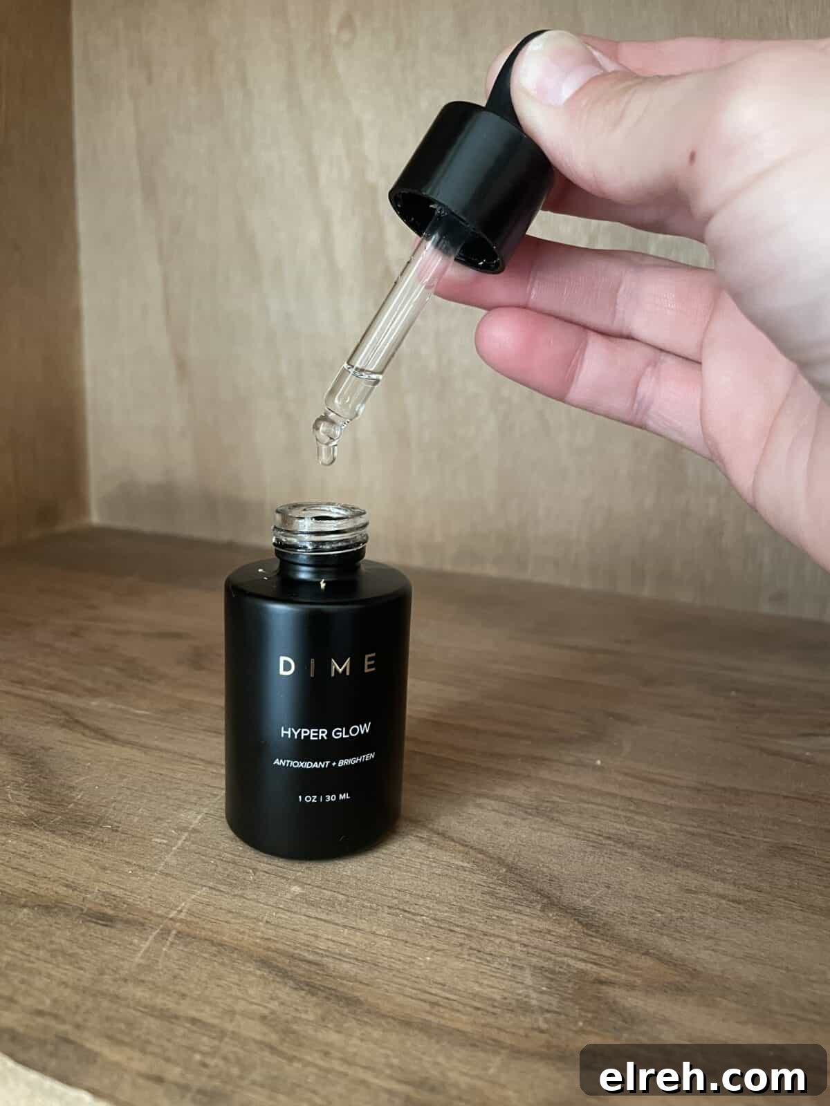 a bottle of dime serum with a hand holding the lid above