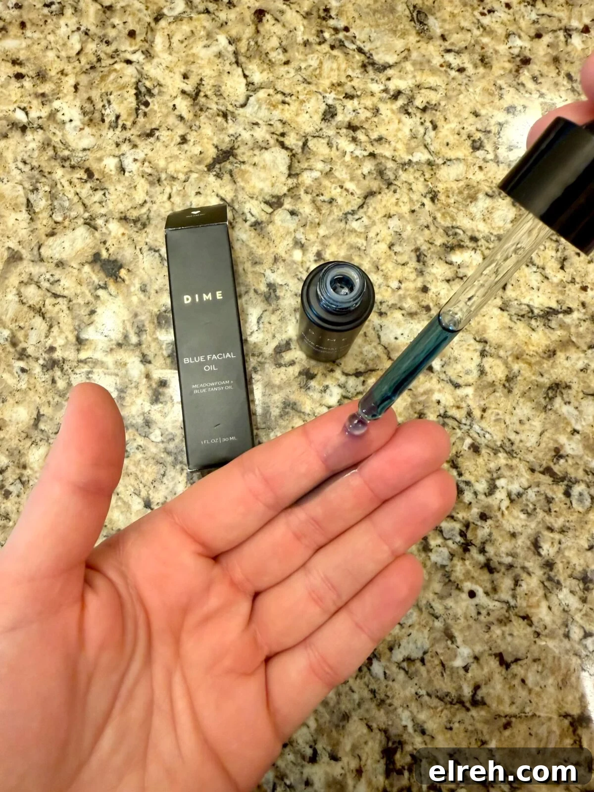A hand holds a dropper with blue liquid above an open palm