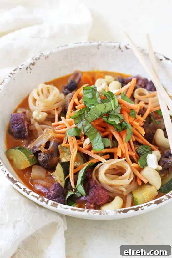 Rainbow vegetable curry noodle bowls with creamy broth, fresh vegetables, and brown rice noodles. Side view of a rainbow vegetable curry noodle bowl with chopsticks and a white napkin.