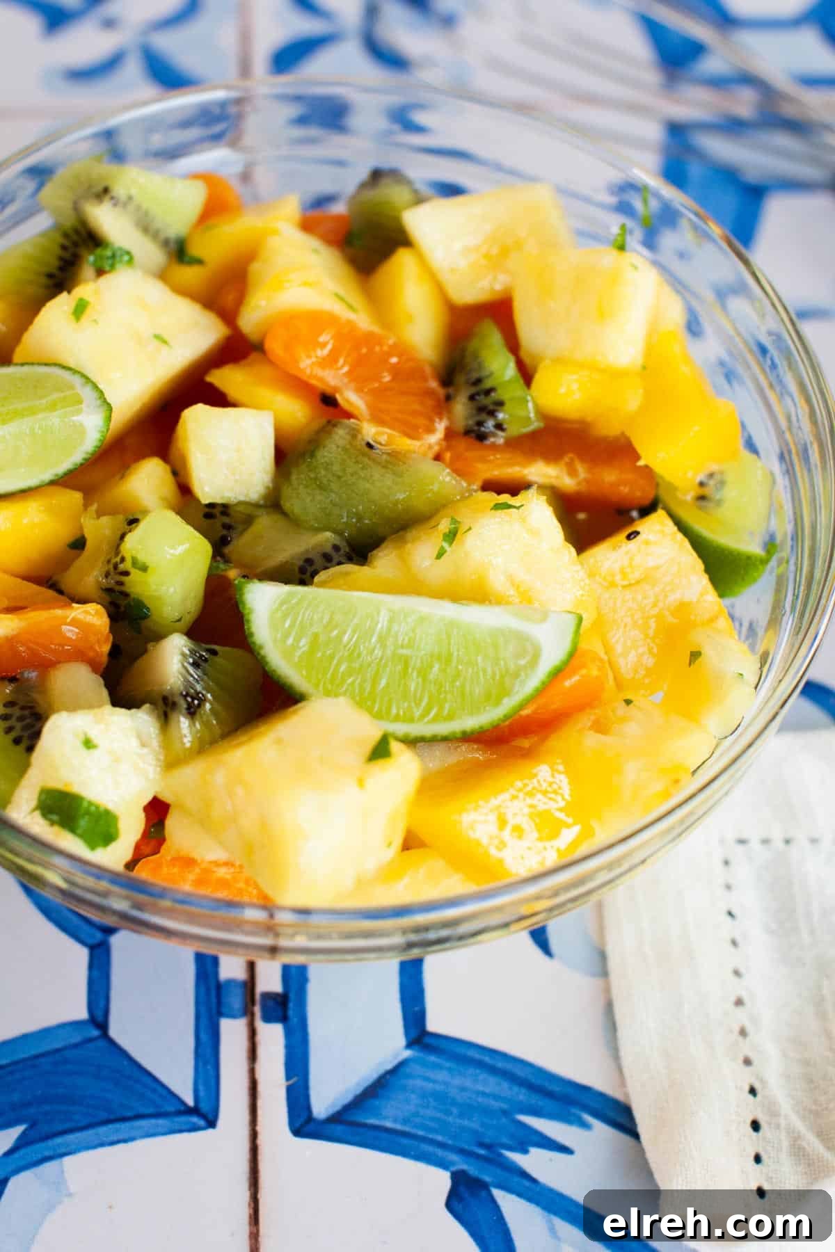A bowl of fruit salad on a blue and white tiled table.