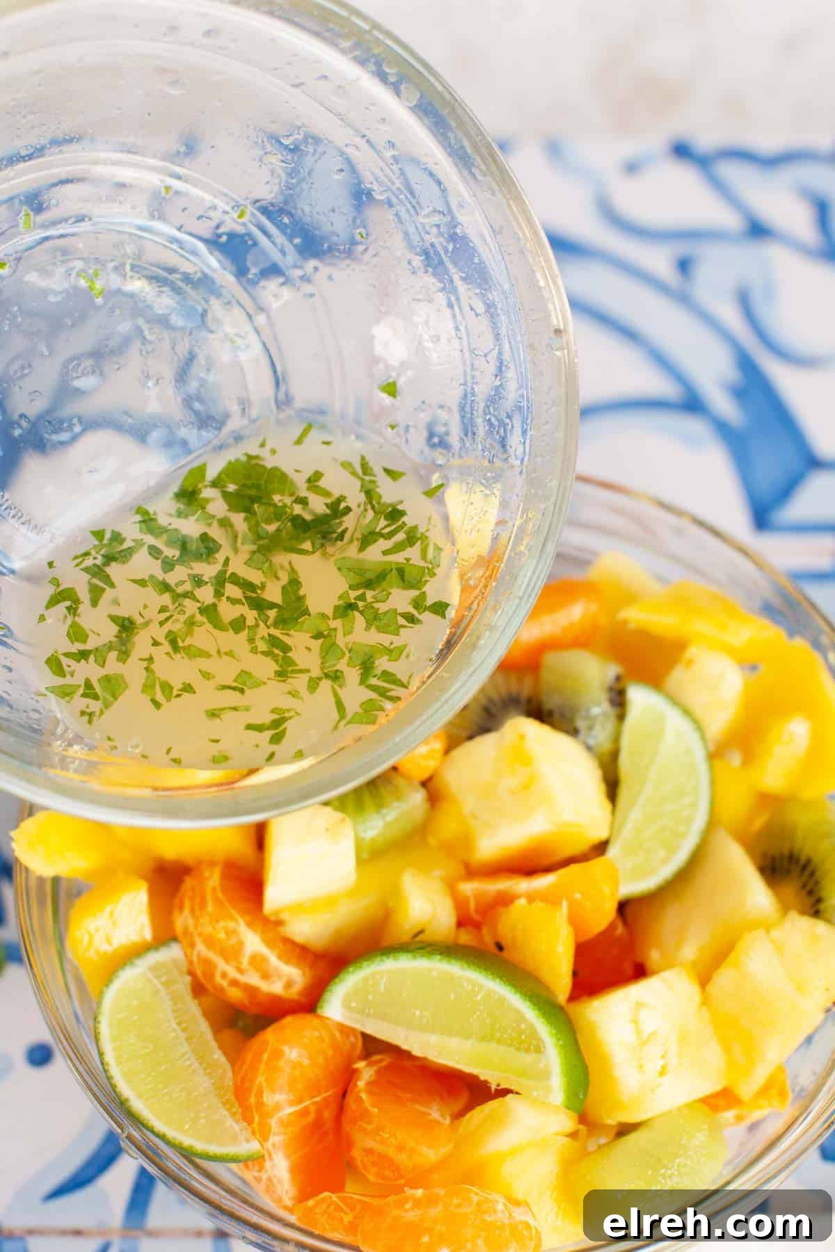 Lime dressing being poured onto Mexican fruit salad.