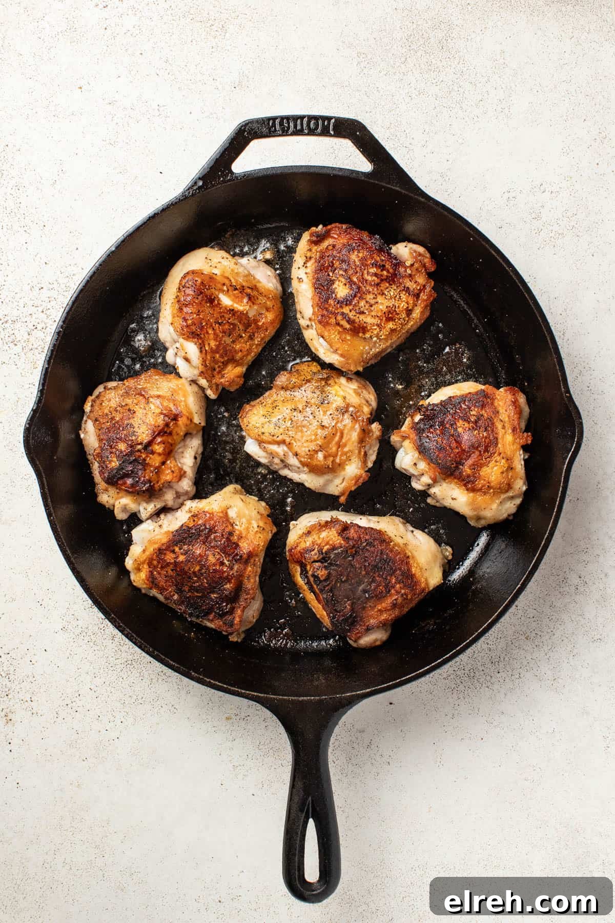 Chicken thighs after being seared in a cast iron pan.