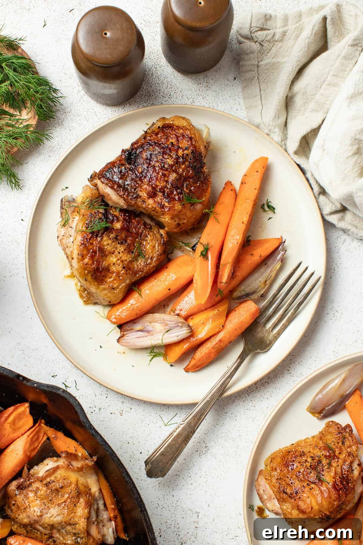 Crispy chicken thighs and carrots on a white plate with a fork.