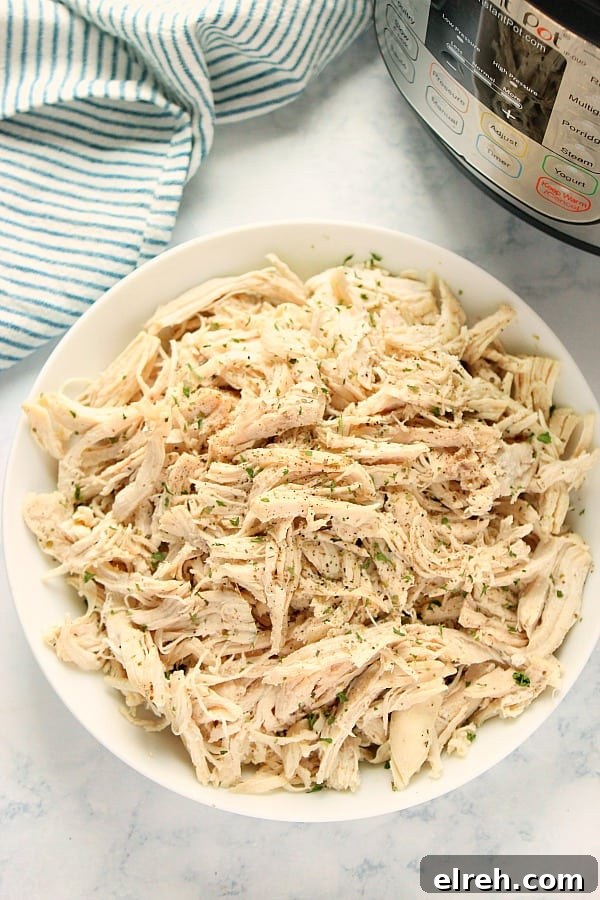 Make delicious shredded chicken in your Instant Pot, in 30 minutes! So easy and it only requires 5 ingredients! Overhead shot of shredded chicken in white bowl.