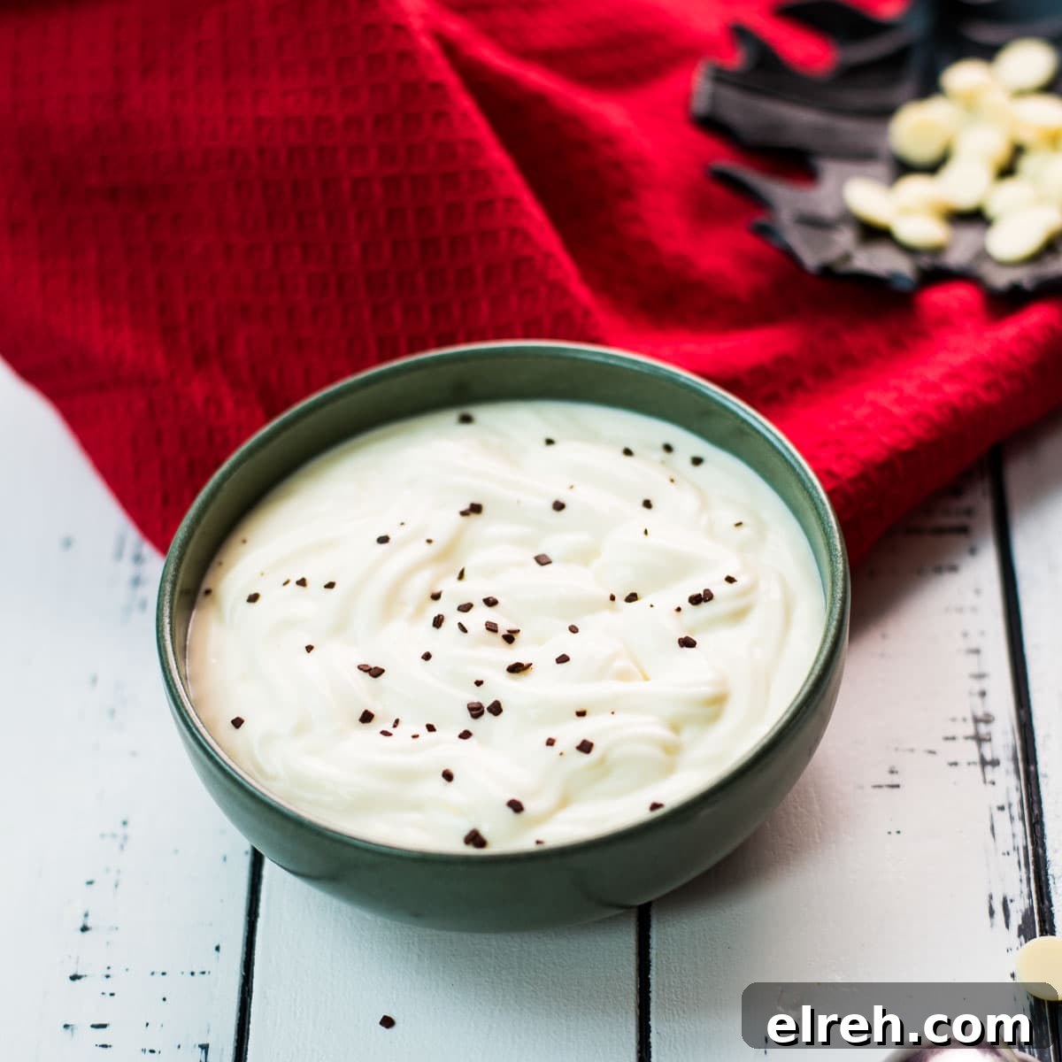 White Chocolate Pudding Recipe to Impress Guests 10 Gorgeous green bowl on white wooden board filled with delicious white chocolate pudding.