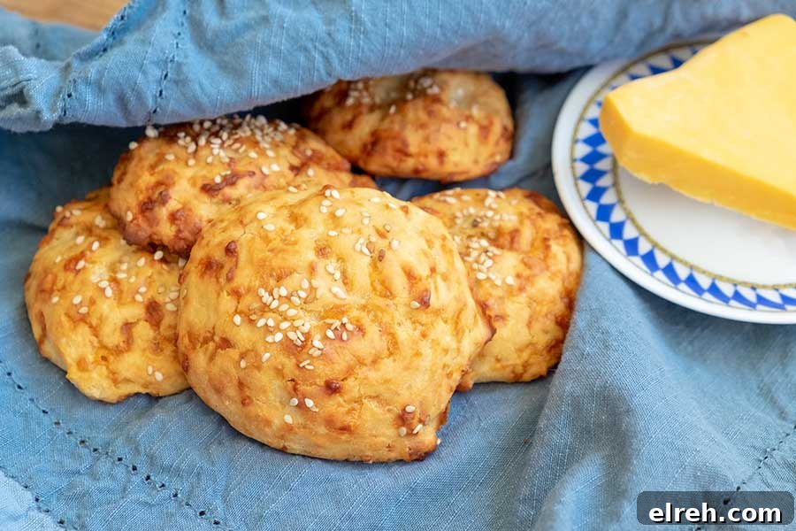 11 Gluten-Free Rolls and Buns: Soft, Fluffy Recipes 10 Tender, cheesy gluten-free 4-ingredient cheese buns on a blue towel with a side of butter.