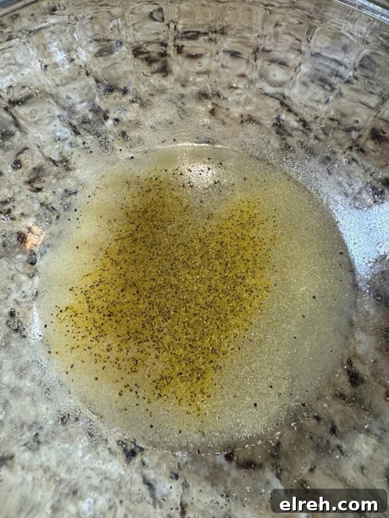 A lemon juice dressing with seasonings in a glass bowl