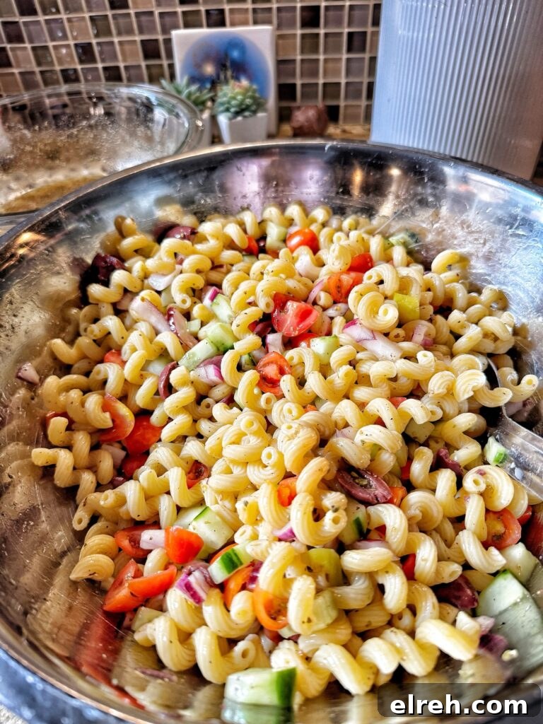 The finished Greek Pasta Salad in a metal bowl with a metal serving spoon