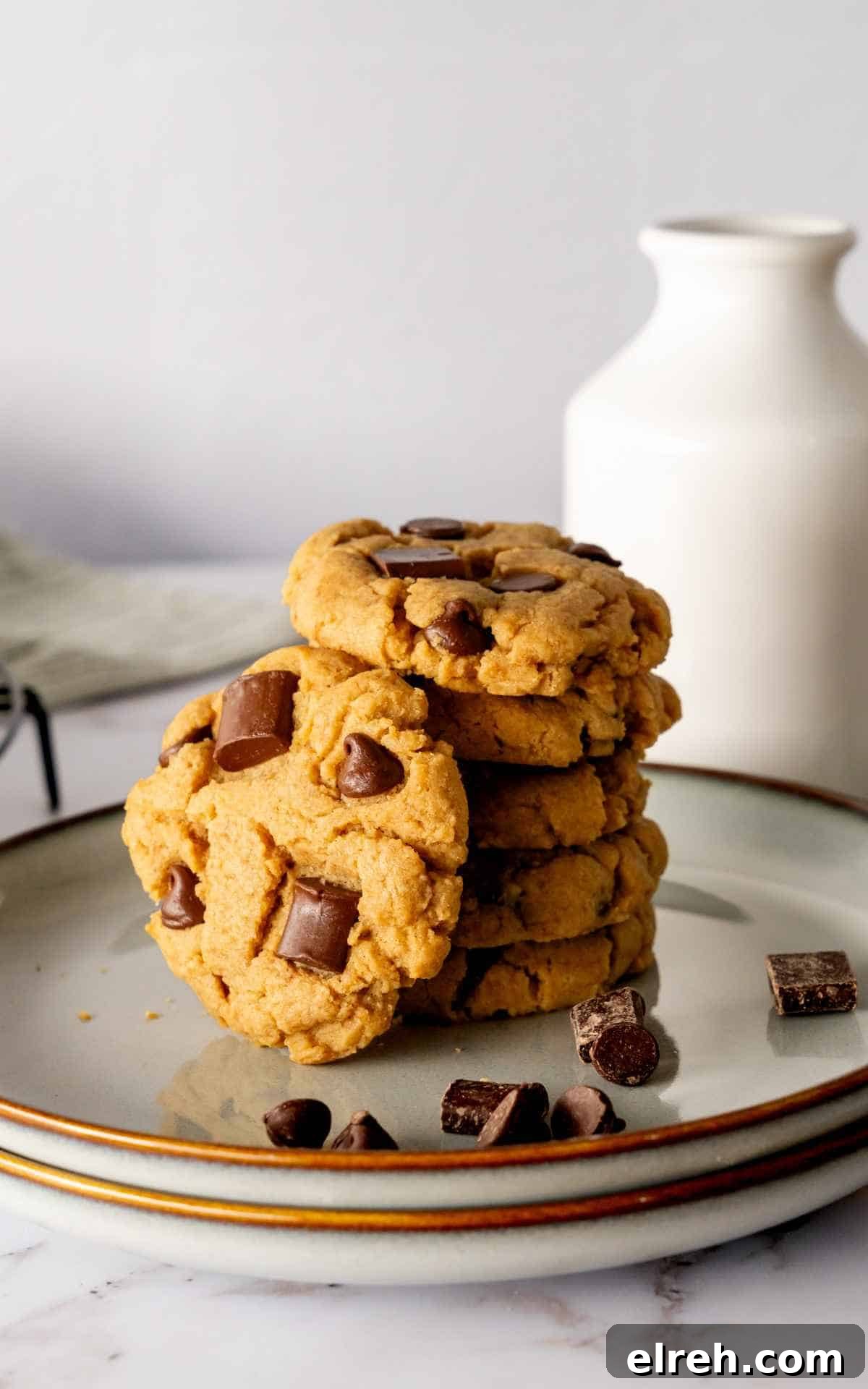 Chewy Peanut Butter Chocolate Chip Cookies Recipe 4 A stack of peanut butter chocolate chip cookies on a plate with a glass of milk behind it.