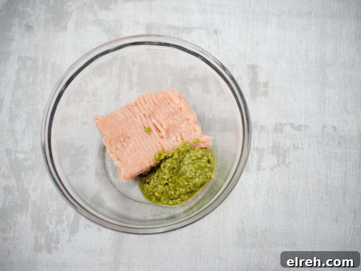 raw chicken and pesto in glass bowl