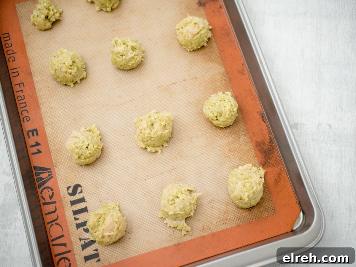 raw chicken pesto meatballs on a baking sheet lined with a silpat
