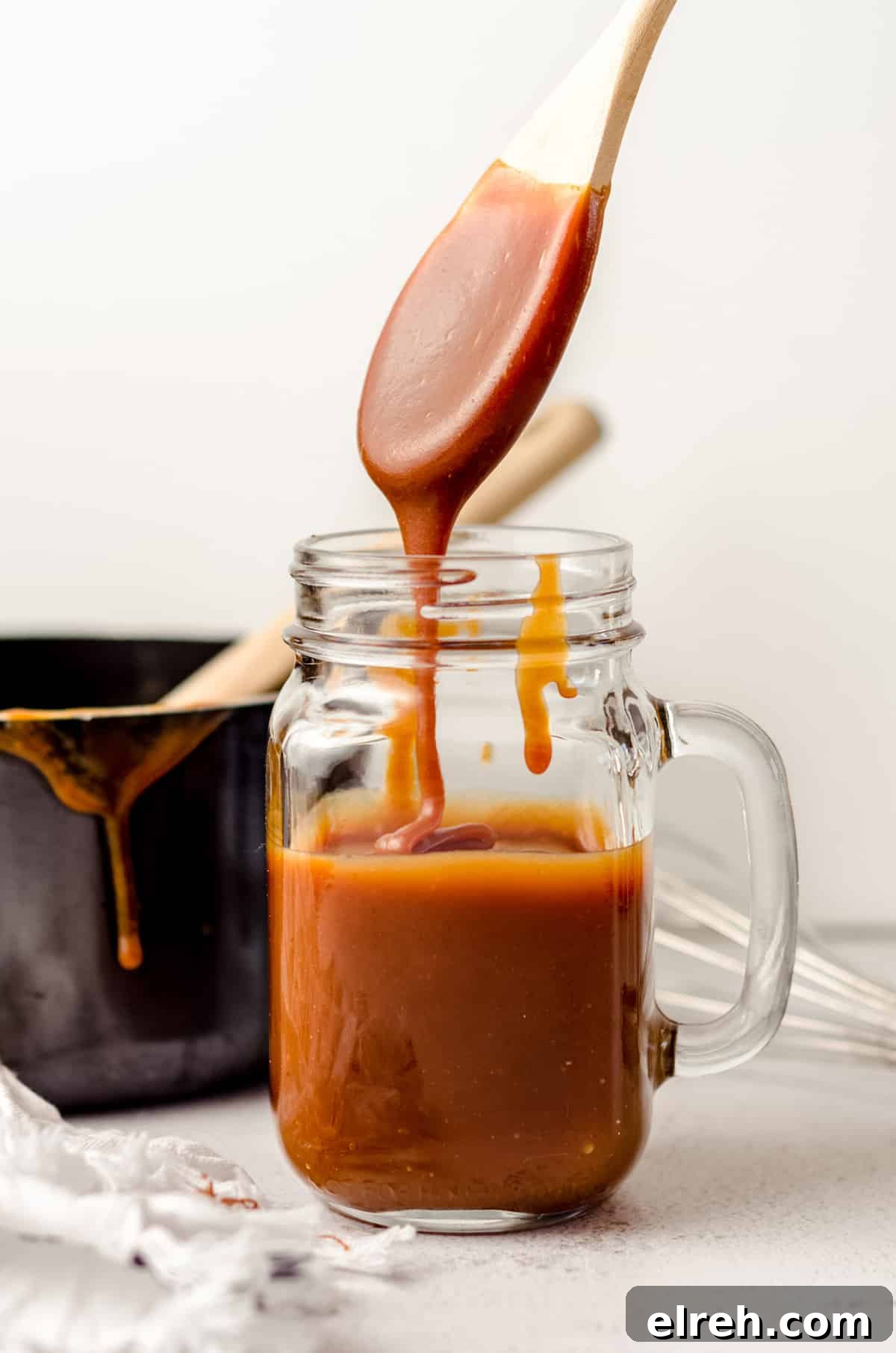 jar of salted caramel sauce with a spoon dipped into it dripping back into the jar
