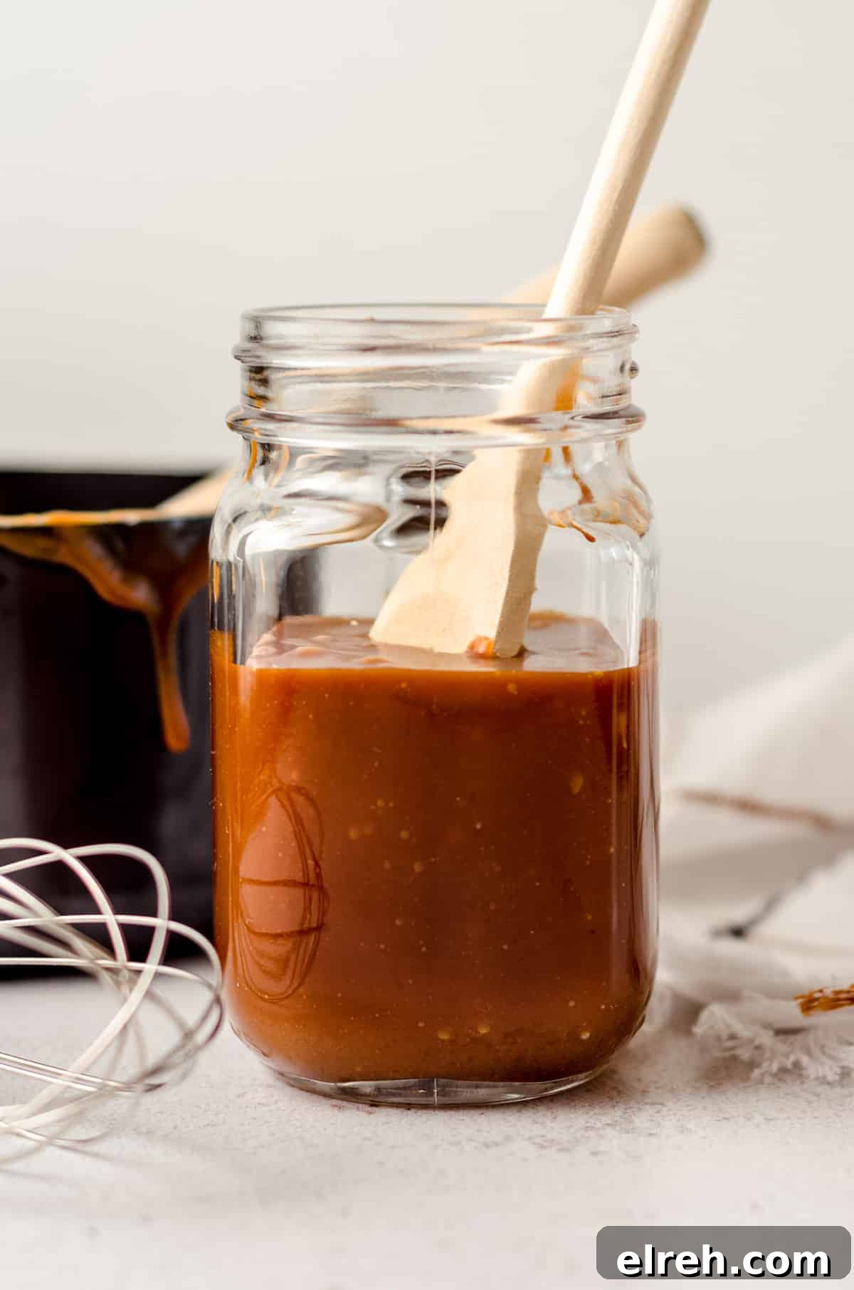jar of salted caramel sauce with a wooden spoon sitting in it