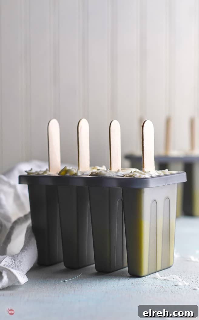 Creamy Mango Pina Colada Popsicles Recipe 7 grey popsicle molds filled with sticks sticking out