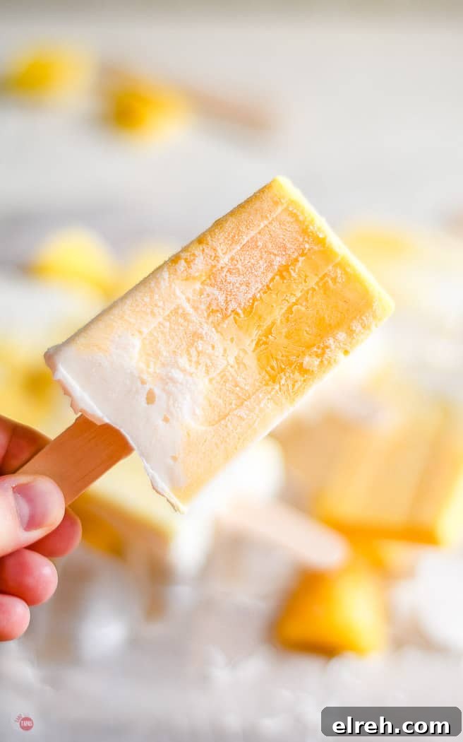 Creamy Mango Pina Colada Popsicles Recipe 8 close up of hand holding tropical popsicle