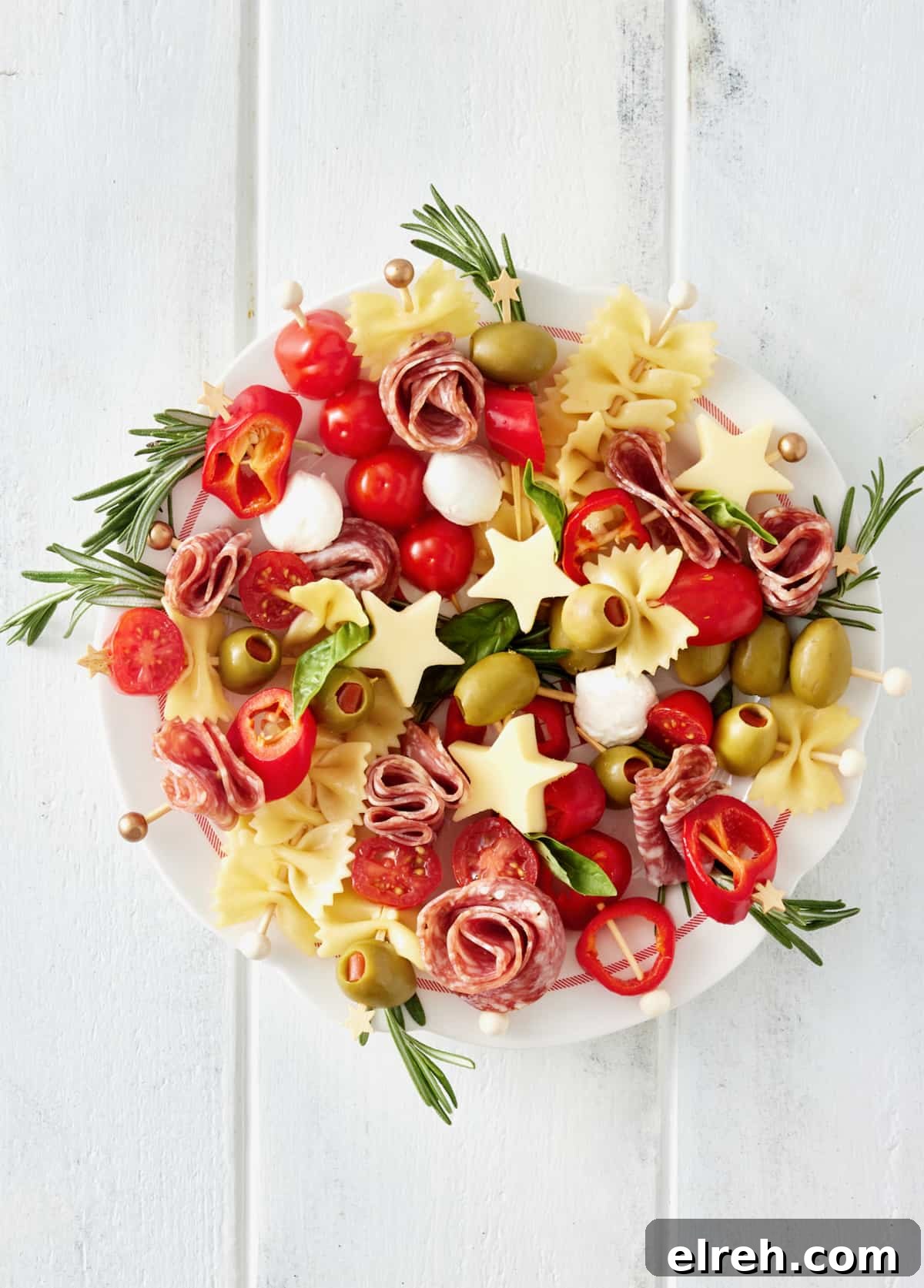 Throw an Ugly Sweater Holiday Party: Ideas and Tips 7 A large white serving plate with skewers made of meats, olives, peppers and cheeses laid out in a circle to look like a holiday wreath.