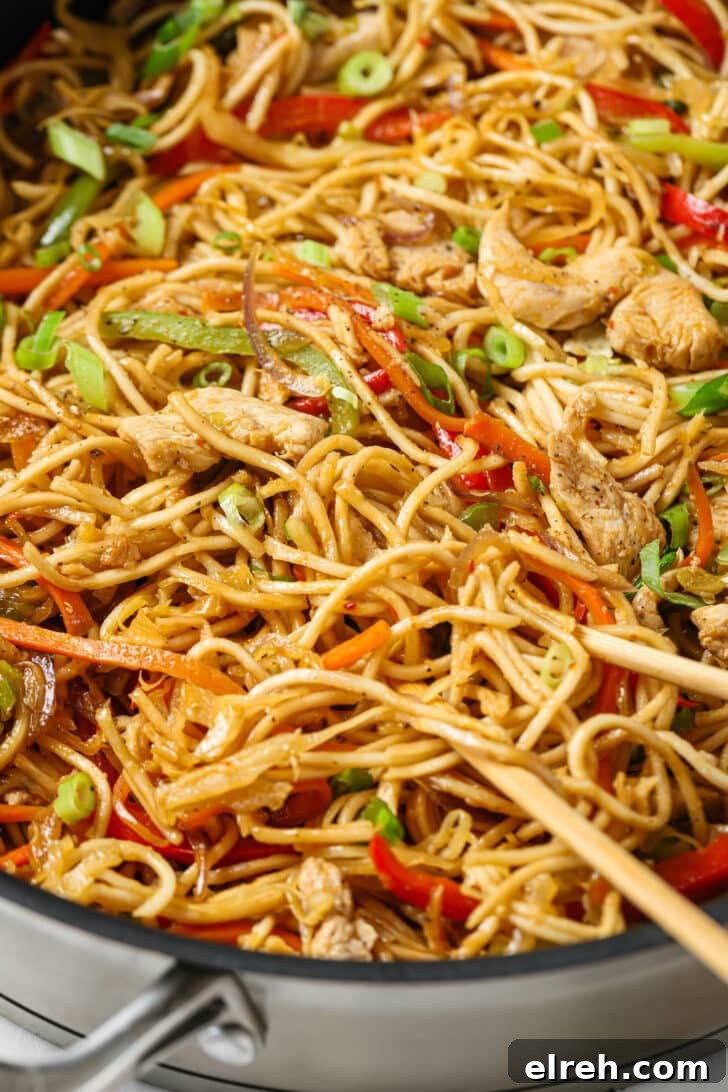 Close up of skillet of Hakka Noodles garnished with green onions with chopsticks.