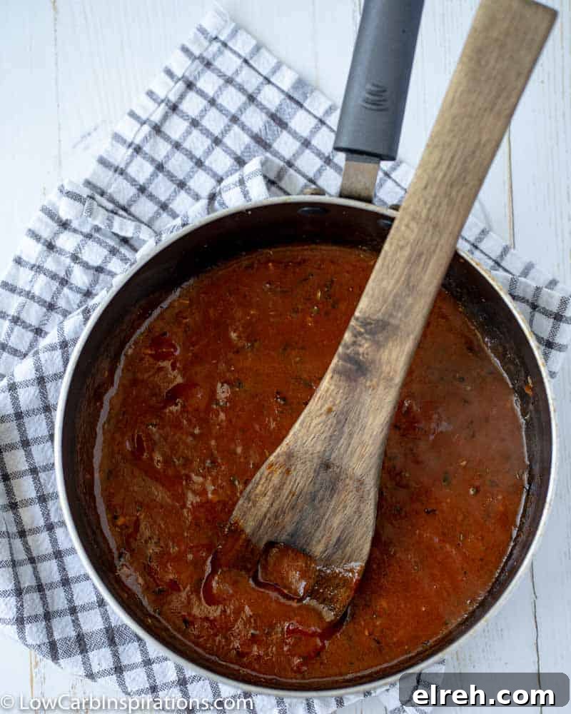How to Make Mushroom Pizza with Cauliflower Crust 14 pizza sauce in a saucepan with a wooden spoon