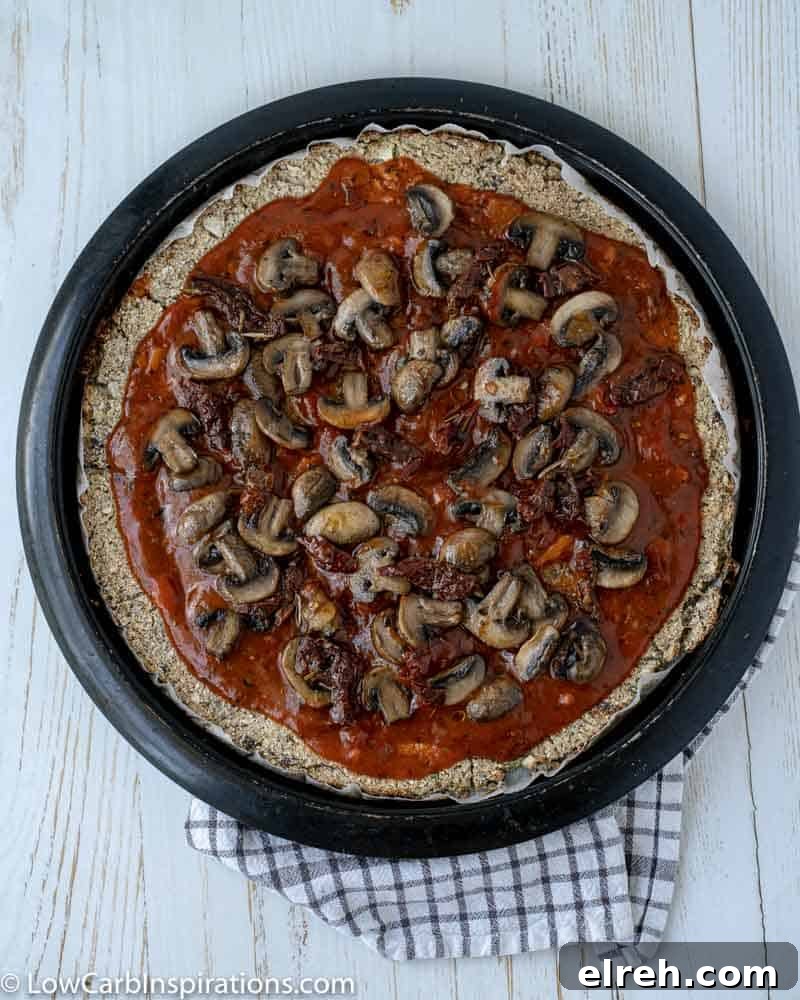 How to Make Mushroom Pizza with Cauliflower Crust 15 cauliflower pizza crust with sauce and cooked mushrooms on a pizza pan