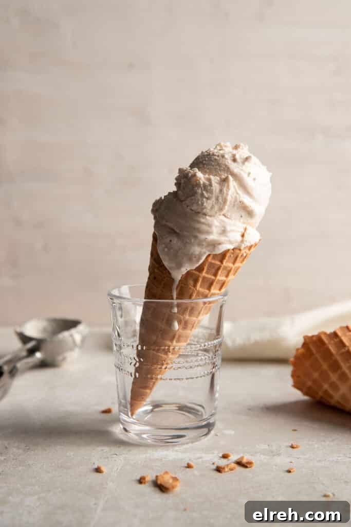 chai ice cream in a waffle cone held up by a clear drinking glass