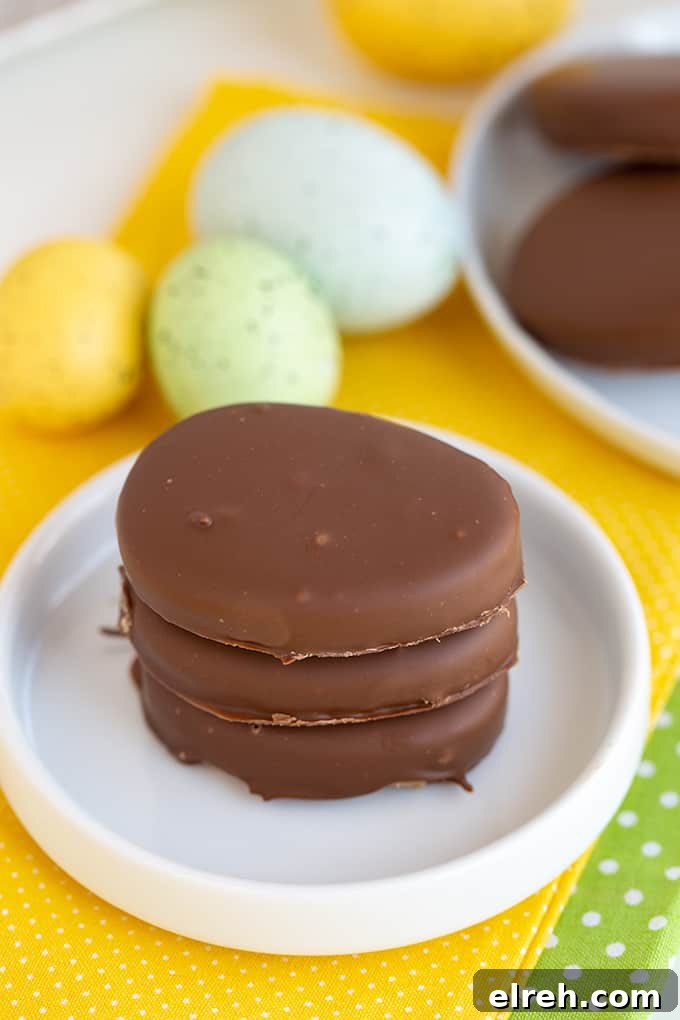 Chocolate Peanut Butter Eggs Recipe 7 stack of pb eggs on a rimmed white plate with yellow linen under the plate