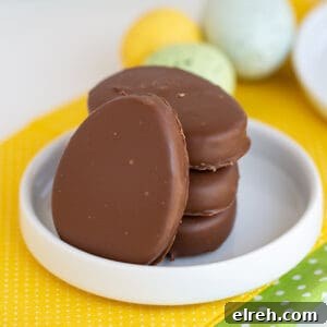 Chocolate Peanut Butter Eggs Recipe 10 square image of pb eggs stacked on a small rimmed white plate on a yellow fabric with speckled eggs behind it