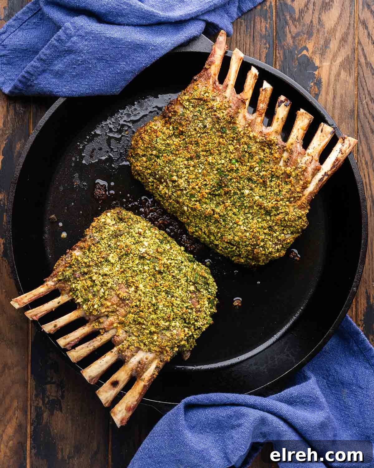 Herb crusted rack of lamb in cast iron pan with blue napkins.