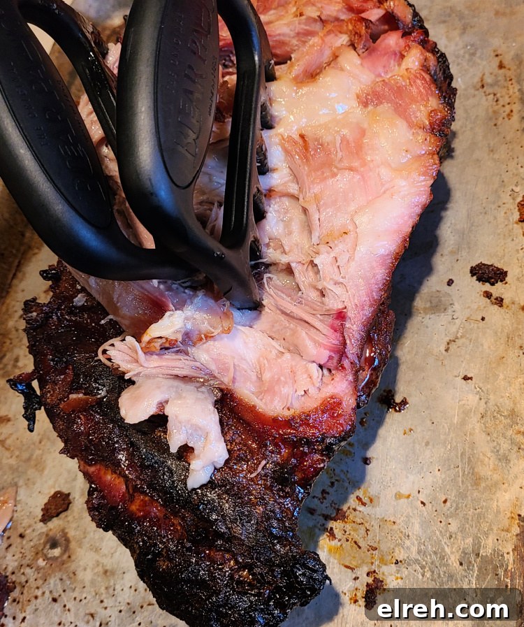 Jim Beam Apple Bourbon Smoked Pork Shoulder being shredded with meat claws