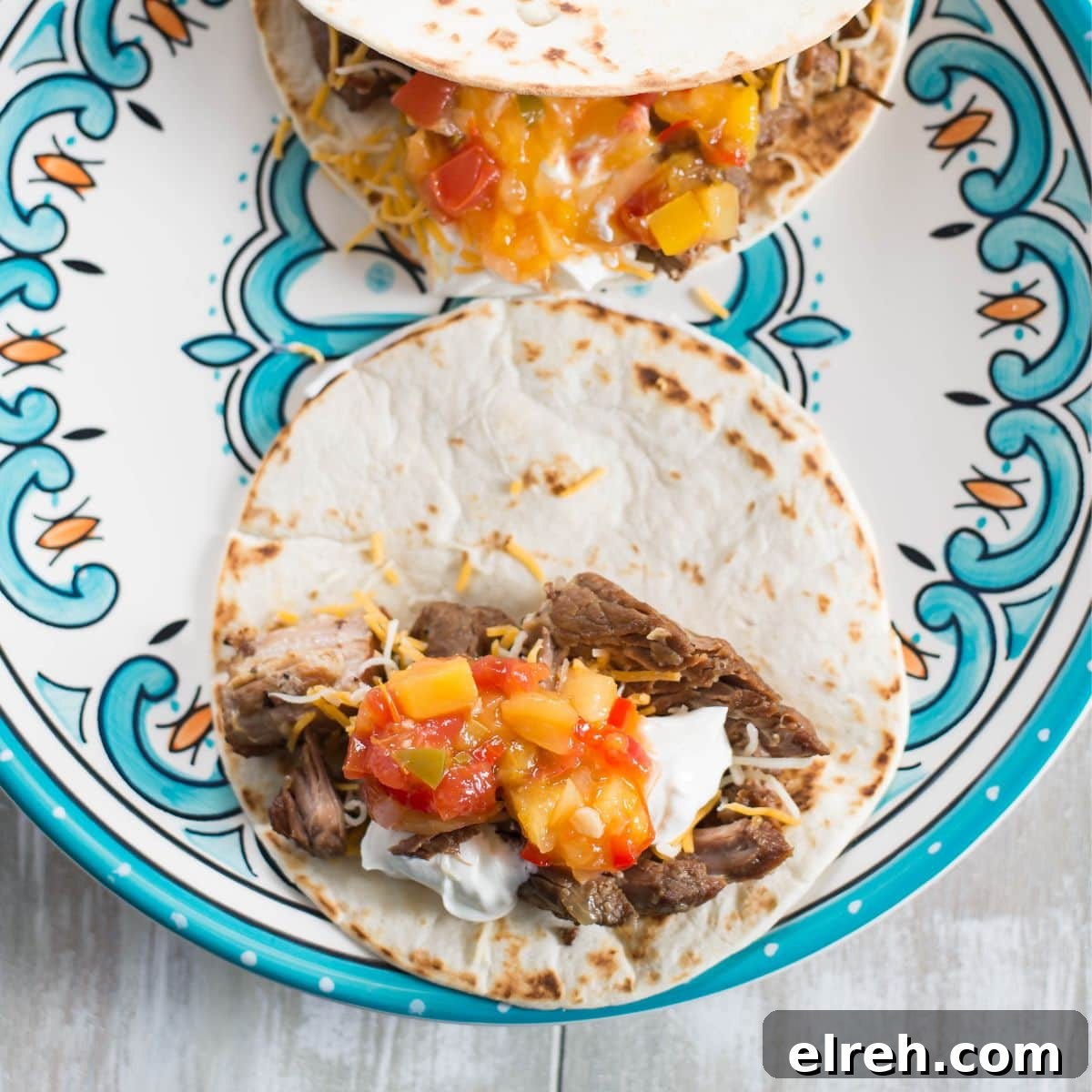 Slow Cooker Pork Carnitas for Tacos 2 Tender shredded pork carnitas meat piled on a tortilla with salsa.