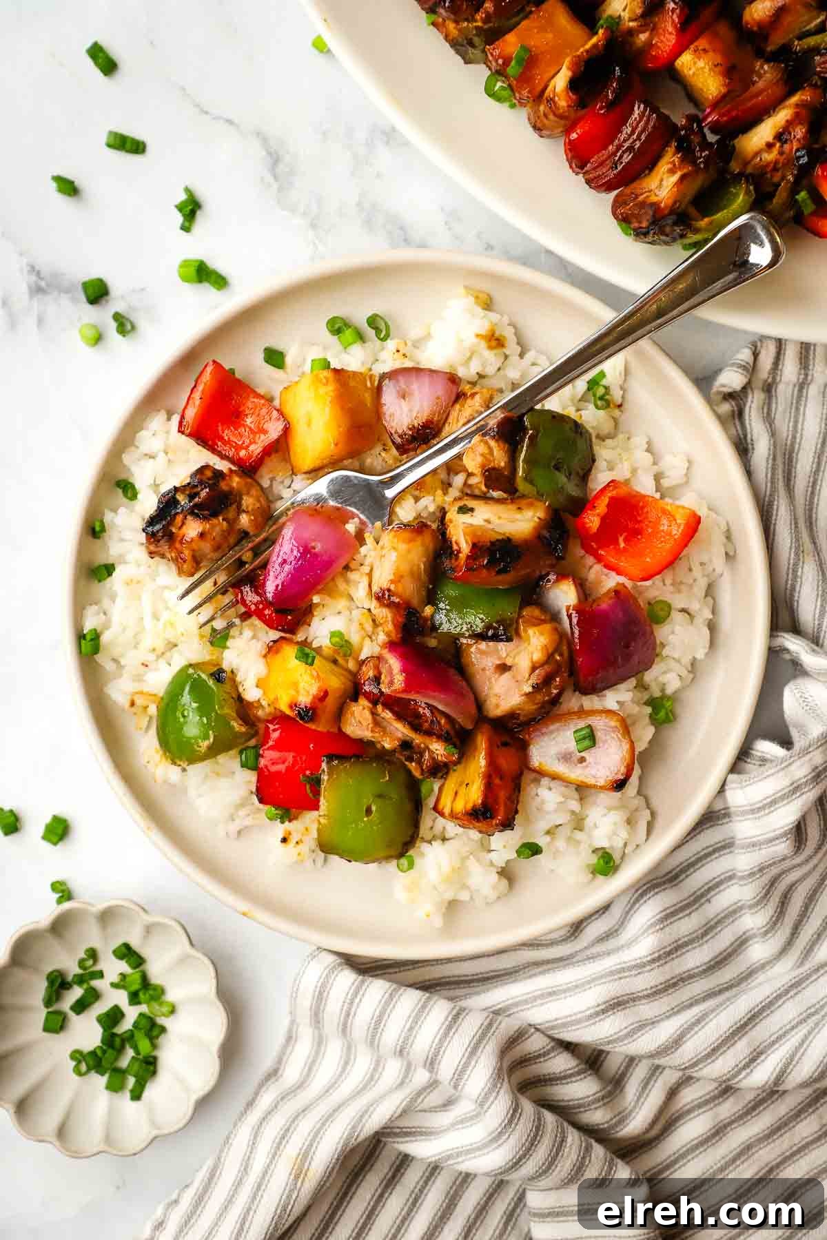 a plate of teriyaki chicken and vegetables served over rice.
