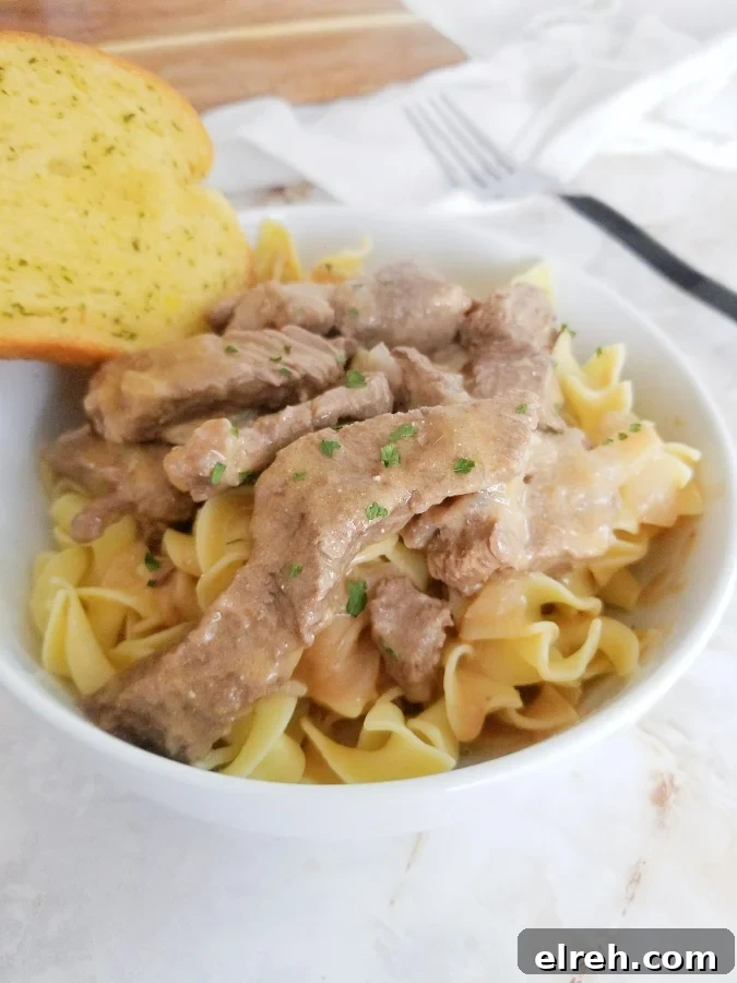 Mom's Creamy Beef Stroganoff with Sliced Steak 2 Mom's Beef Stroganoff in white bowl with garlic bread