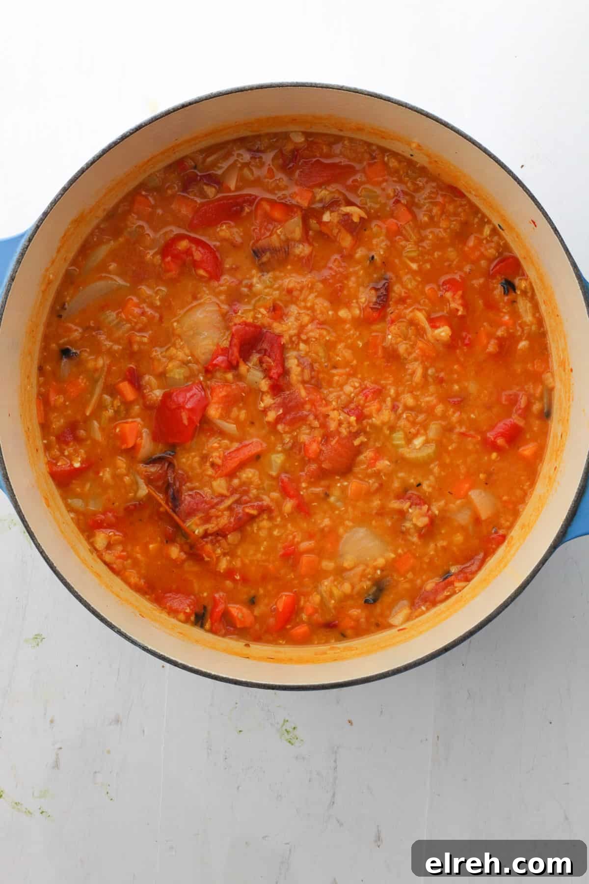 A Dutch oven with lentil and red pepper soup cooking.