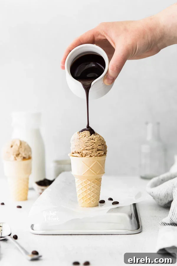 No Churn Coffee Ice Cream in an ice cream cone with chocolate sauce being poured on top