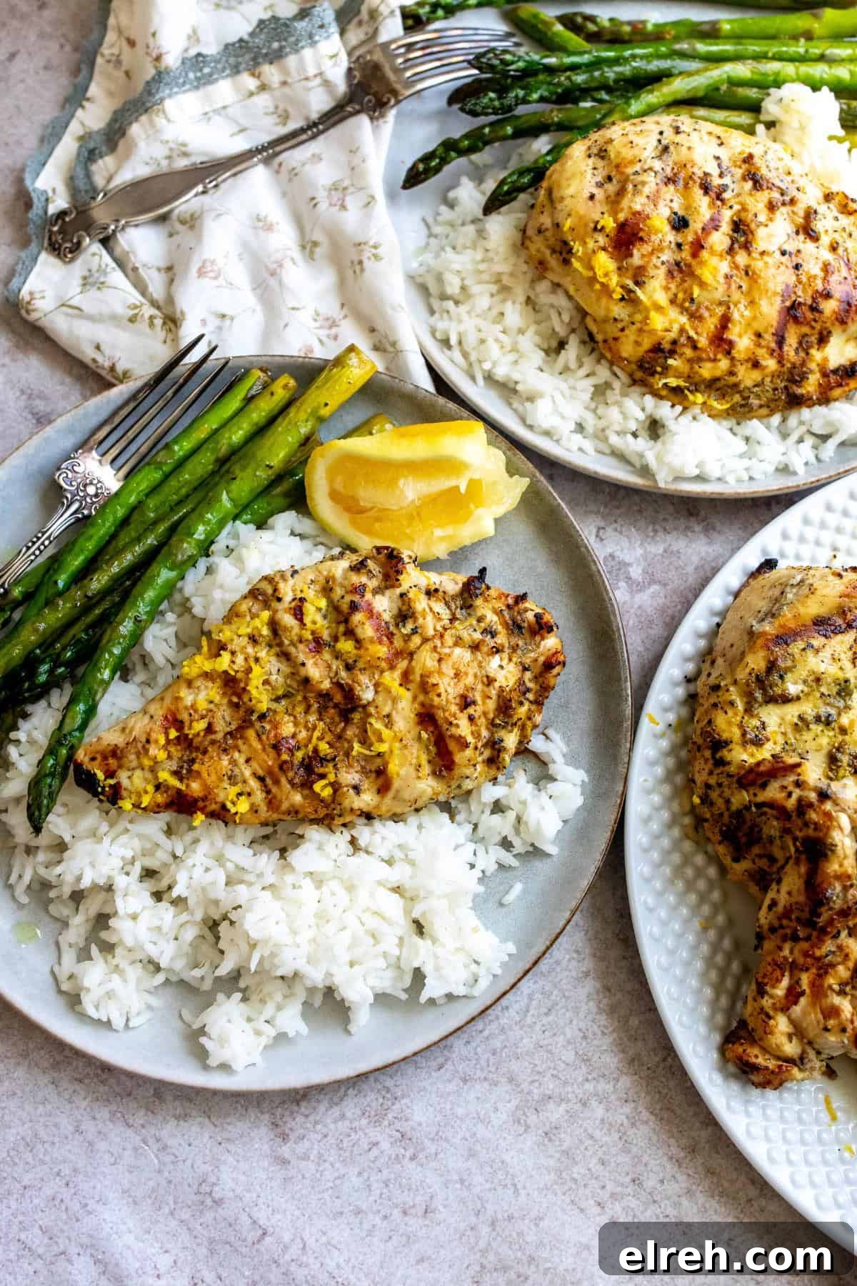 Garlic Lemon Herb Chicken Recipe 2 Grey plates with lemon pepper chicken on rice and lemon wedges on the side.