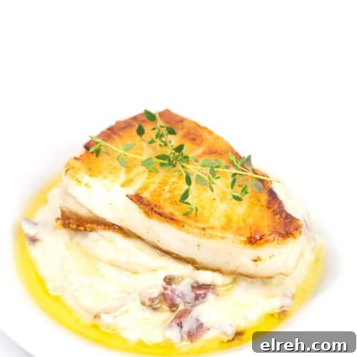 a plate of pan seared sea bass with mashed potatoes with a butter sauce and fresh herbs garnish