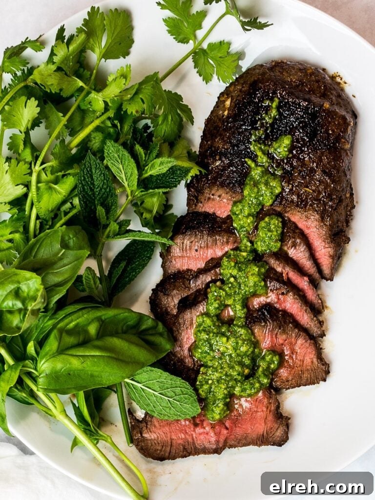 Asian marinated flank steak, spicy Asian chimichurri steak with fresh herbs on a white plate
