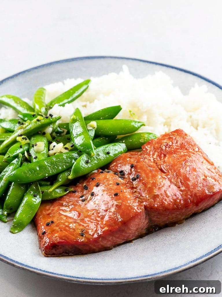 Baked teriyaki salmon with sugar snap peas and rice on a blue plate