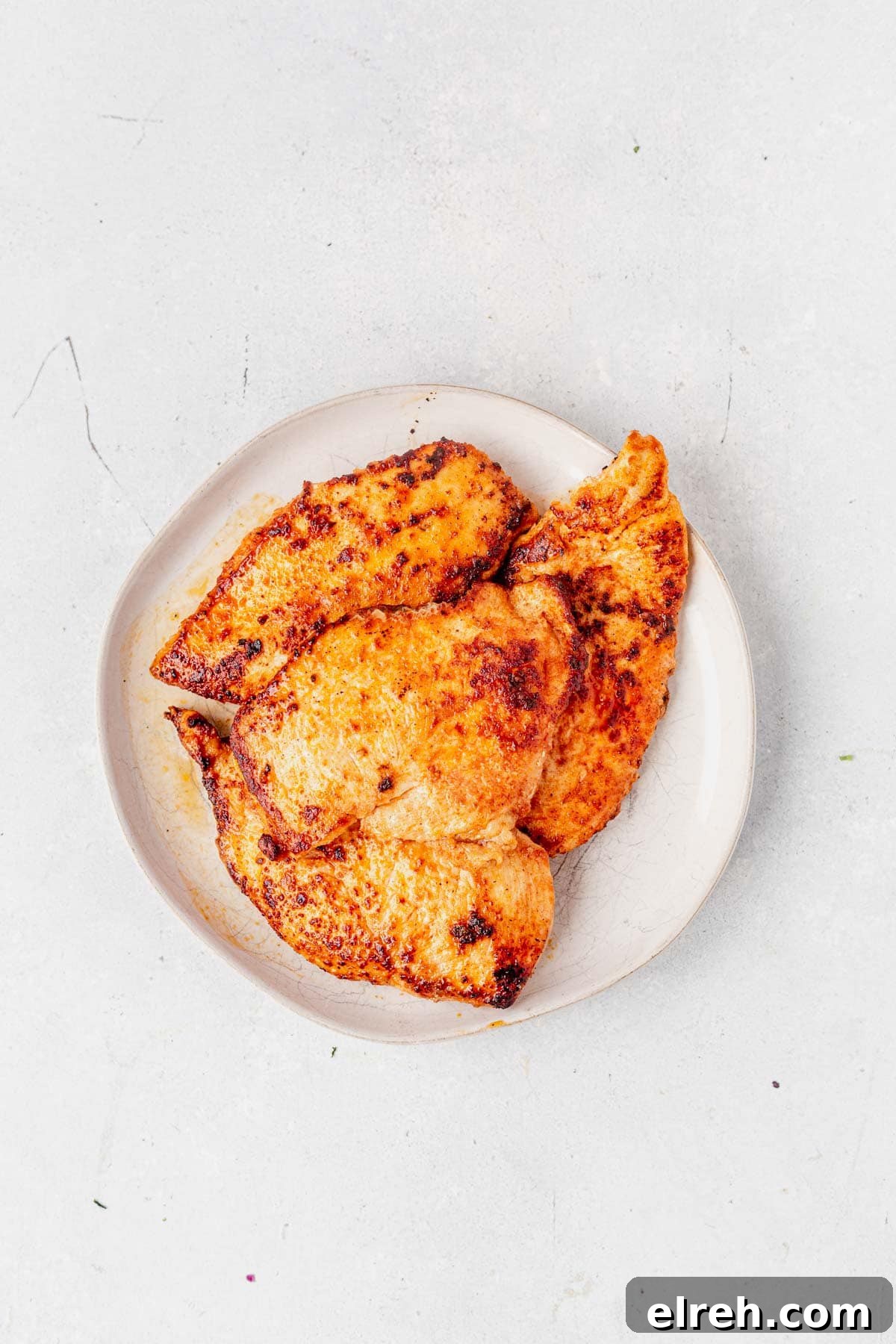 seared chicken breast for boursin chicken recipe on a white plate on the counter