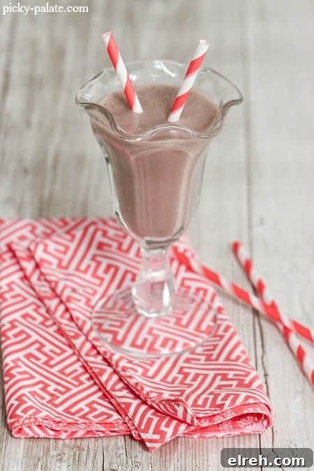 Refreshing Summer Drink Recipes to Beat the Heat 3 A chocolate banana peanut butter smoothie in a fountain glass with two red-striped straws.