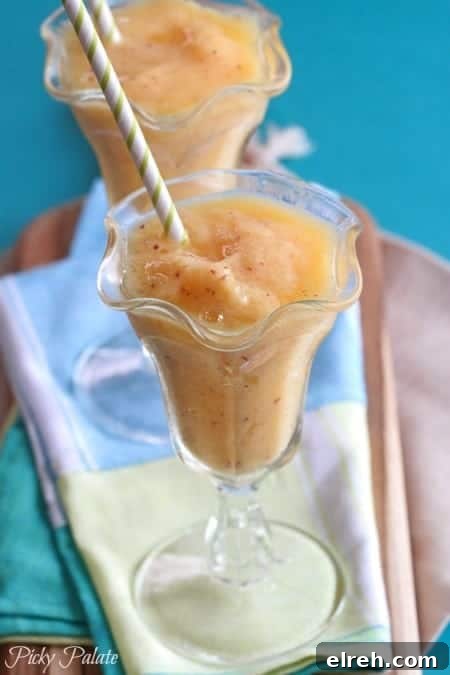 Refreshing Summer Drink Recipes to Beat the Heat 7 A mango peach slushy in a fountain glass with a straw.