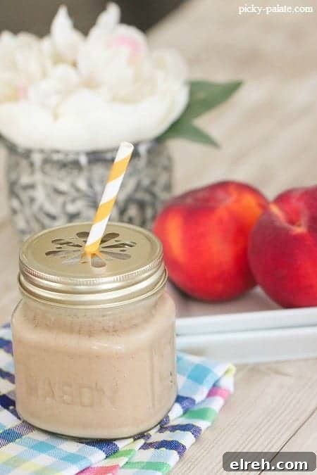 Refreshing Summer Drink Recipes to Beat the Heat 9 A peaches and cream frosty in a glass mug with a lid and a yellow-striped straw.