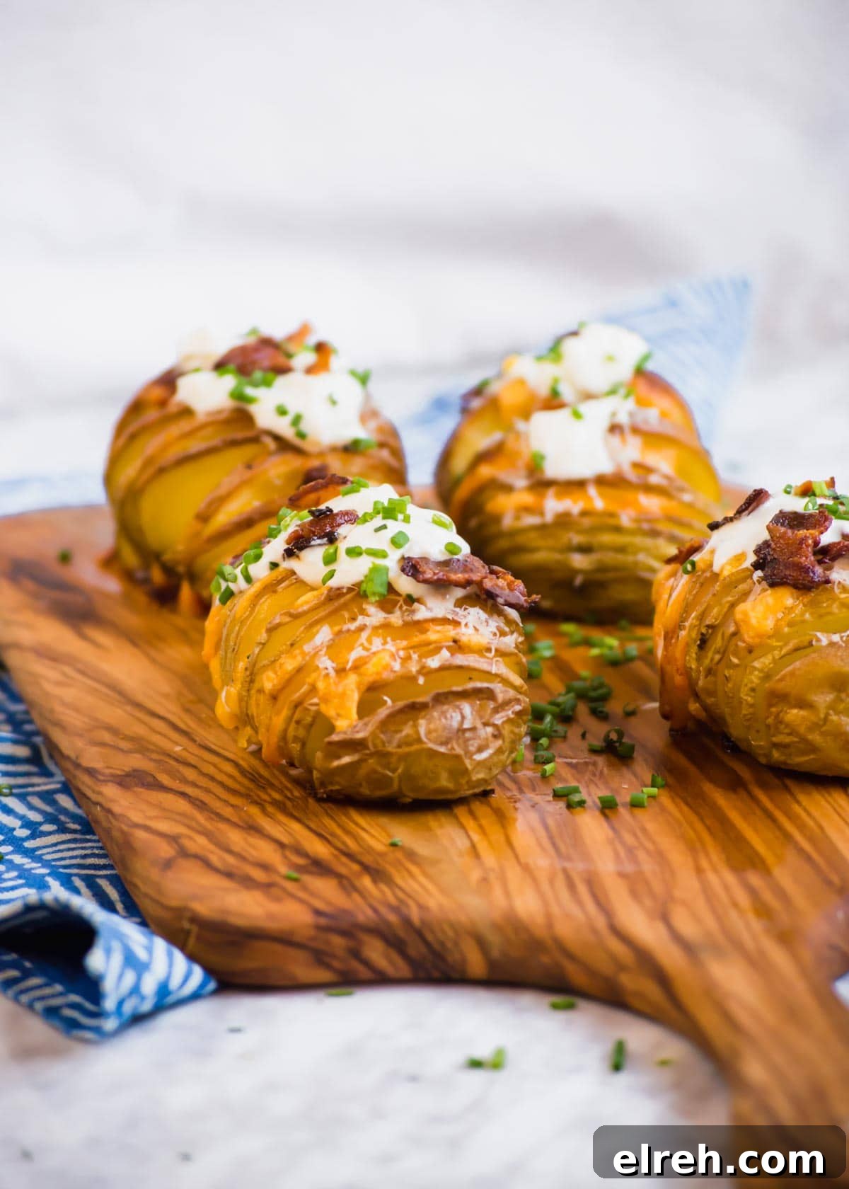 22 Delicious Sides to Serve with Chicken Wings 3 Bacon Cheddar Hasselback Potatoes on cutting board.