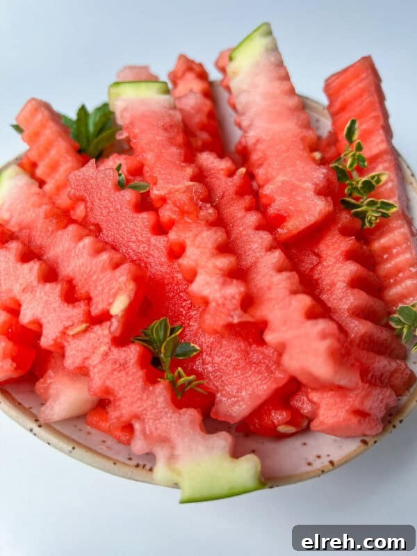 A bowl filled with crinkle-cut watermelon fries, garnished with small green herb sprigs.