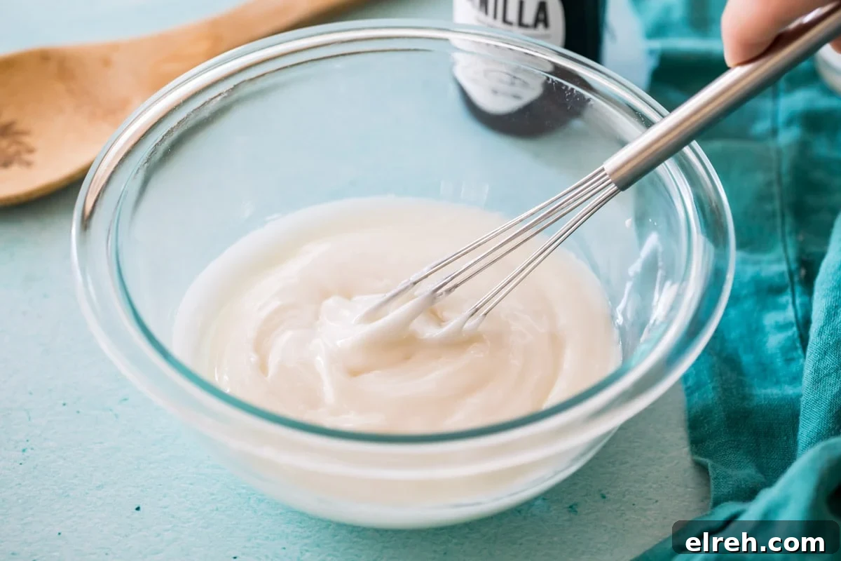 whisk stirring a glaze in a glass bowl