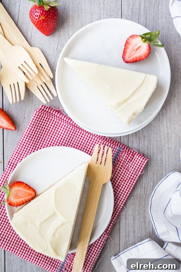 overhead shot of slices of no bake cheesecake on white plates with forks and strawberries. white/red checked napkin and blue/white striped napkin in background