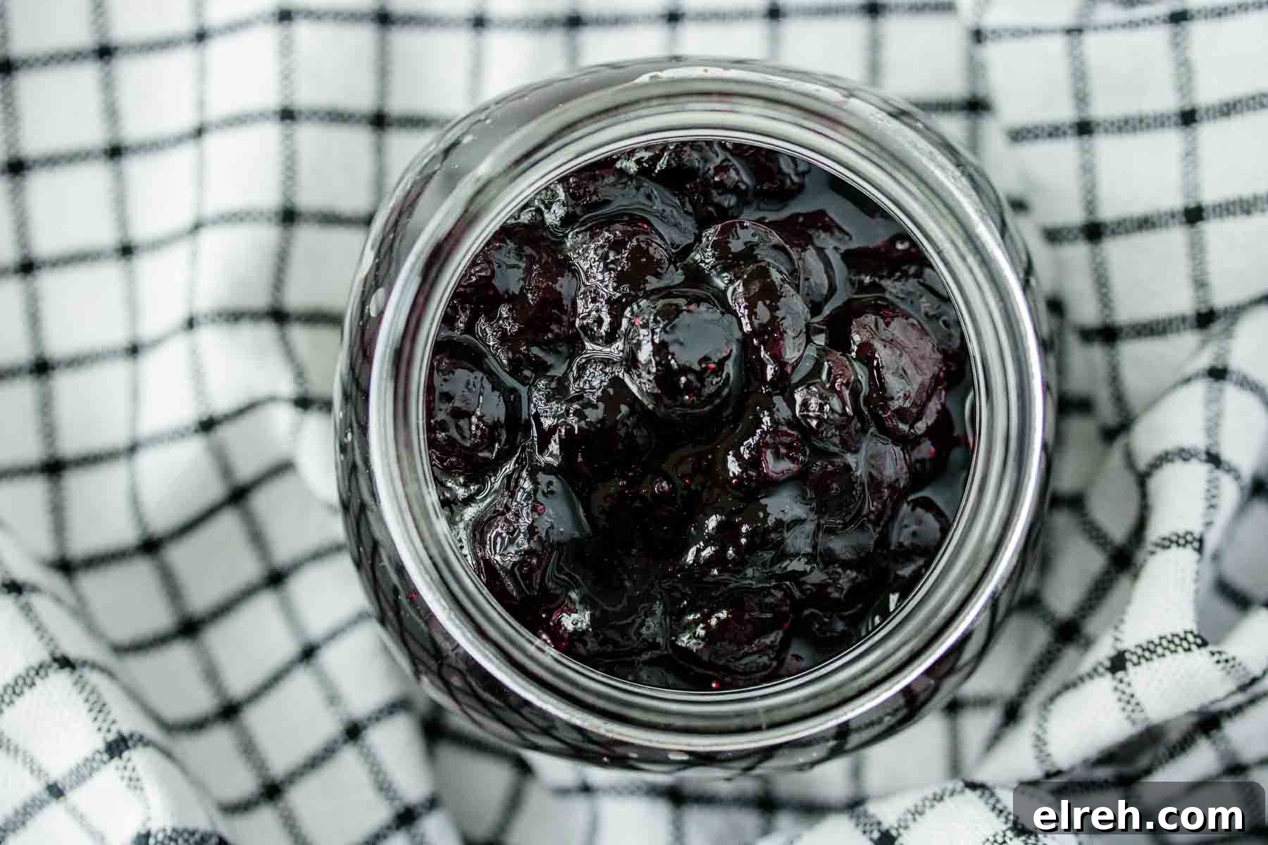 A jar of blueberry compote over a kitchen towel